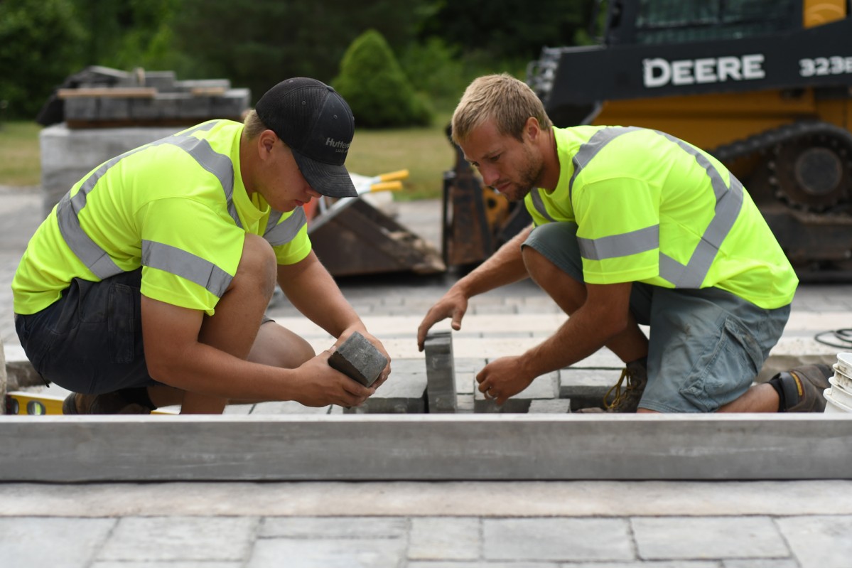 Crew members helping each other install landscape bricks.